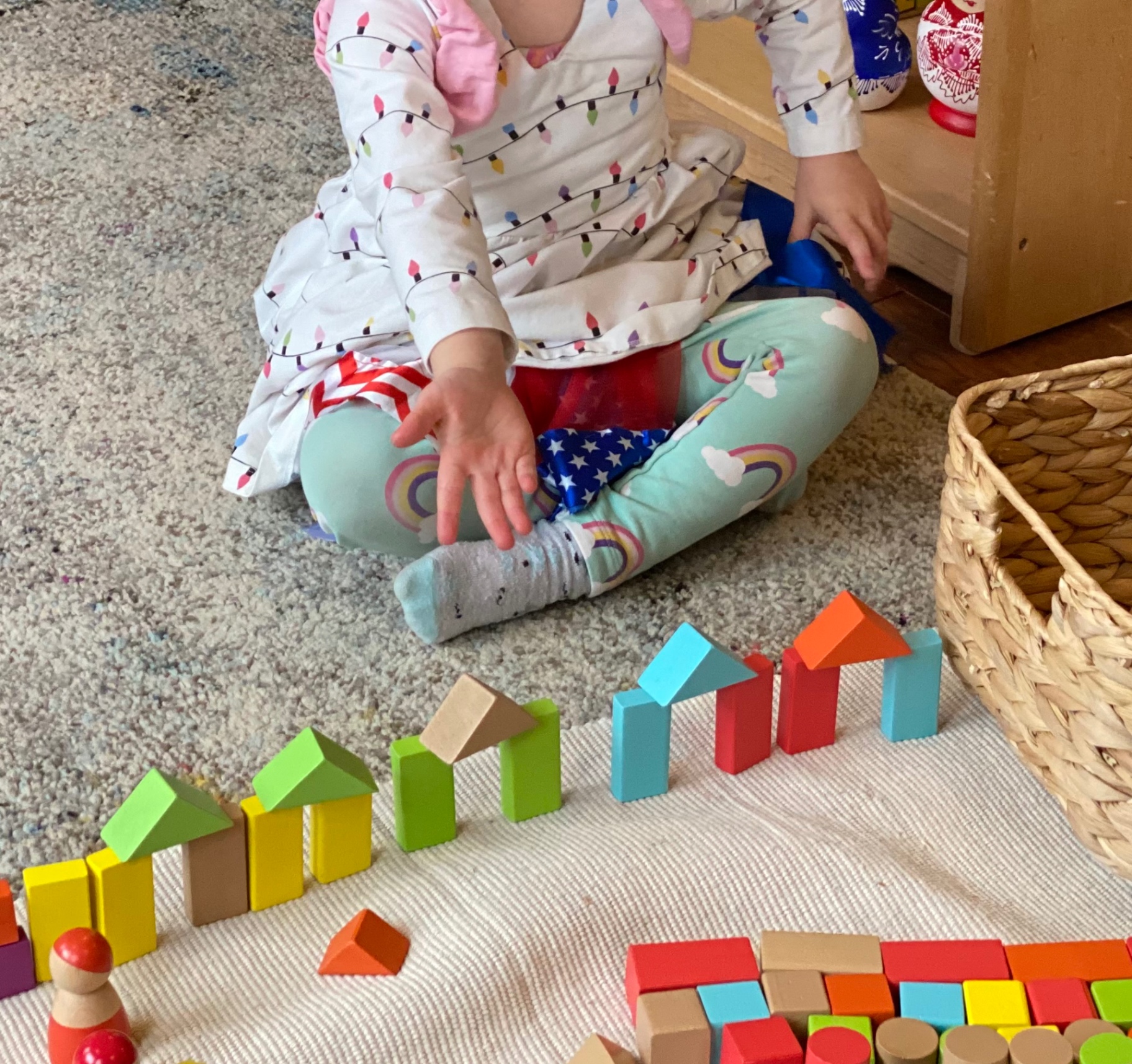 Toddler building a village from rainbow wooden blocks