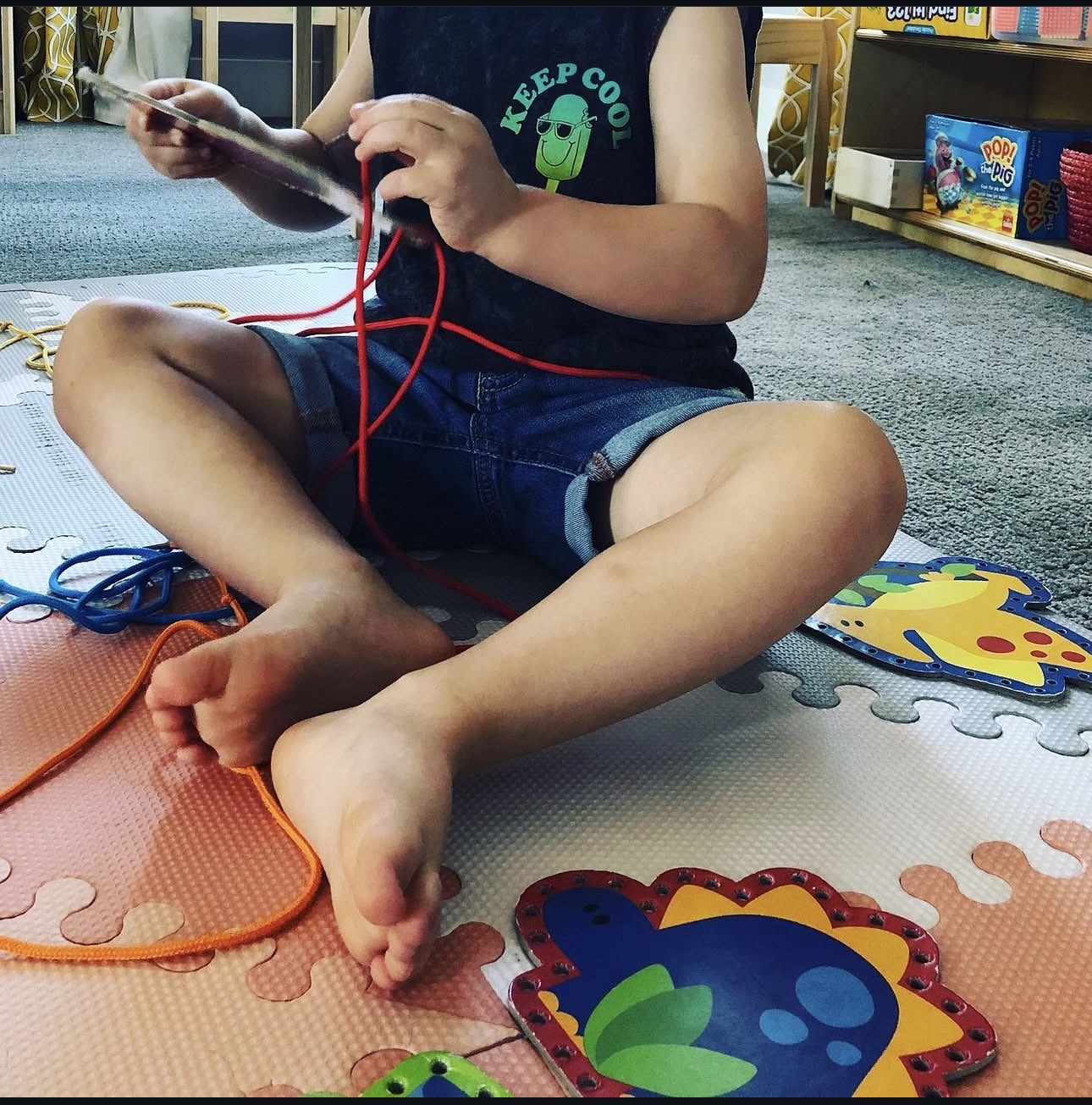 Toddler threading a lacing card in the classroom